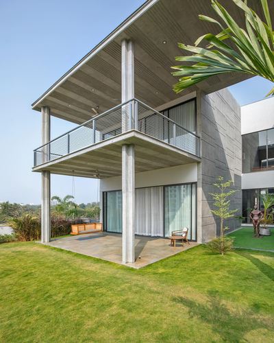 Two-storey concrete house with cantilevered ribbed ceiling, swing, and lawn in Vadodara
