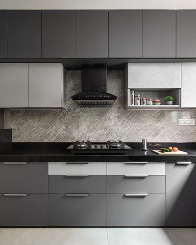 Grey modular kitchen with black chimney hood, granite countertop, and patterned tile backsplash
