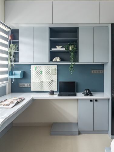 Built-in study desk with blue backsplash, pegboard organizer, laptop, and overhead cabinetry