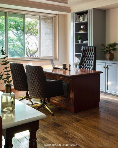 Wood-paneled office with tufted leather chairs facing a classic desk beside a large window
