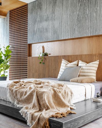 Bedroom with stone accent wall, wood lattice screen, and platform bed with knit throw