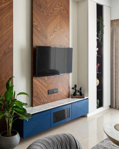TV mounted on chevron wood panel above navy blue floating console with marble top