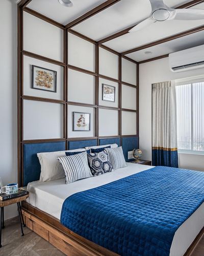 Bedroom with navy upholstered headboard, wood grid paneling extending to ceiling, and city view window