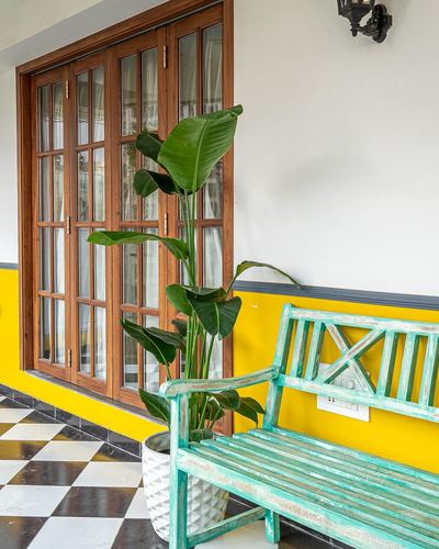 Balcony with wooden folding windows, mustard wall, teal bench, and checkerboard floor