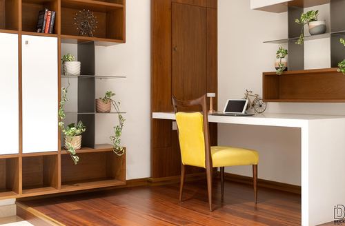Study nook with yellow velvet chair, white desk, and wood shelving with plants