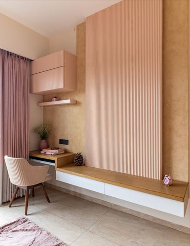 Pink fluted wall paneling above a floating wooden desk and bench with a cane chair