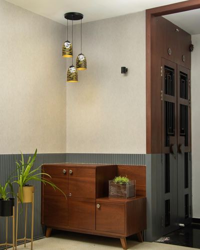 Entryway corner with cluster pendant lights above a wooden console and dark grille door