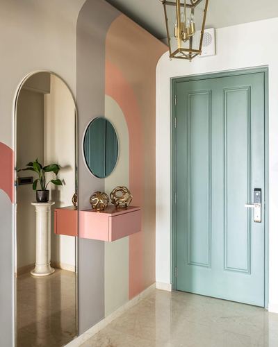 Foyer with arched color-blocked wall, two mirrors, pink console, and sage green panelled door