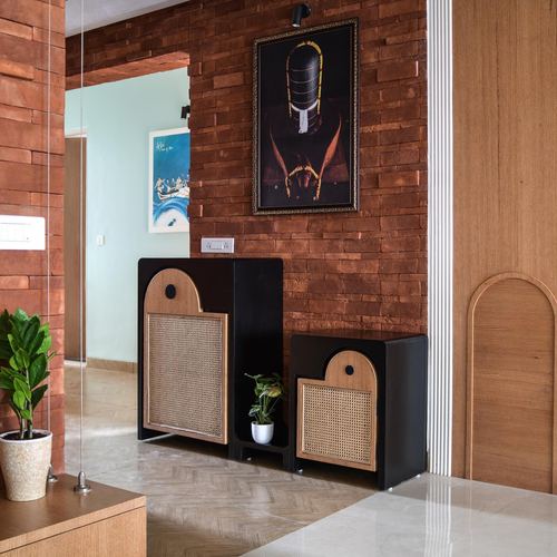 Foyer with exposed brick wall, black cane-front cabinets, framed artwork, and herringbone stone floor