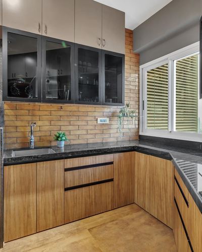 L-shaped kitchen with wood cabinetry, dark stone counters, brick backsplash, and black-framed glass upper cabinets