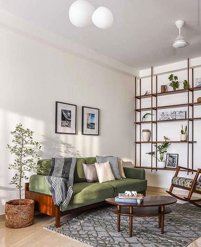 Sunlit living room with green sofa, wooden shelving, round coffee table and patterned rug