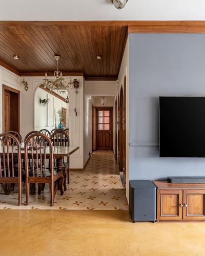 View through dining area with chandelier into living room with wall-mounted tv and wooden ceiling