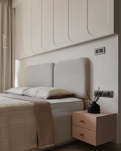 Bedroom corner with fluted paneling, curved upholstered headboard, and blush floating nightstand