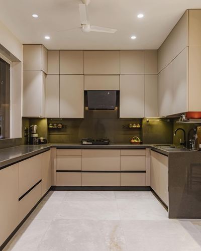 U-shaped modern kitchen with beige fluted cabinetry, olive backsplash, and dark stone countertops