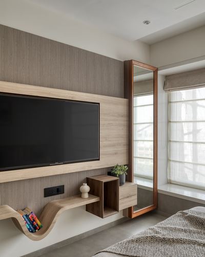 Bedroom TV wall in wood veneer with fluted panelling, floor mirror, and window seat with city view