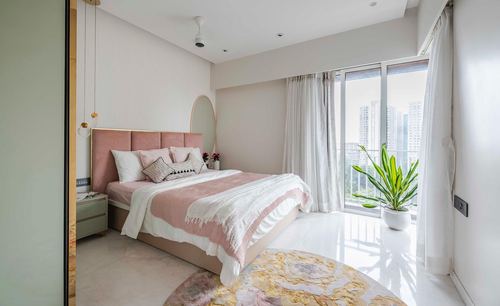 Bedroom with pink tufted headboard, round mirror, sheer curtains, city view and marble floor