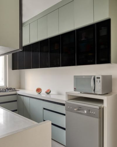 Sage green kitchen with black ribbed glass cabinets, white counter, watermelon slices and steel appliances