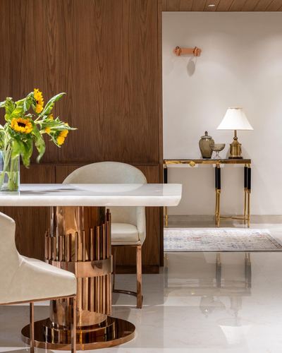 Dining table with fluted metallic base beside console table against wood-panelled wall