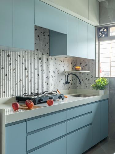 Powder blue modular kitchen with fluted terrazzo backsplash, black gas stove and sink counter