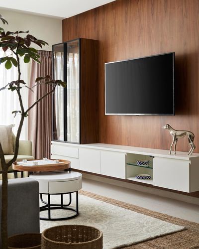 Living room with wood-panelled TV wall, white floating console, and layered round coffee tables on a jute rug