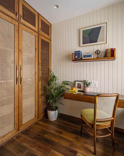 Wooden wardrobe with cane inlay beside a study nook with cane-back chair and shelf