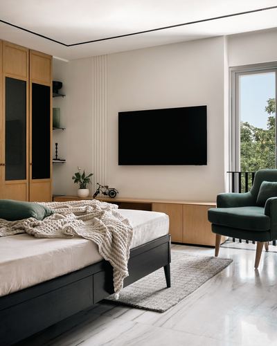 Modern bedroom with black bed, wooden wardrobe, wall tv, and green velvet armchair by window