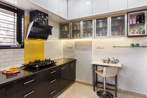 White and black modular kitchen with subway tile backsplash, glass cabinets, and a small breakfast bar stool