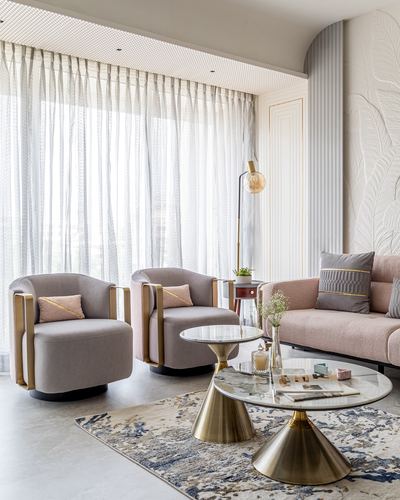 Pink sofa and grey swivel armchairs around brass-based glass coffee tables in a sunlit living room