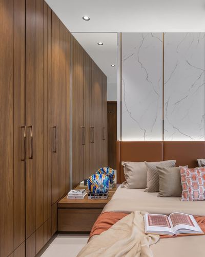 Bedroom with tall wood wardrobes, backlit stone wall panels, and a leather headboard bed