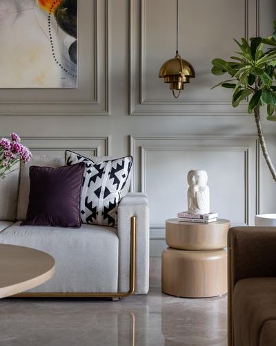 Living room corner with paneled wall, brass pendant light, beige sofa and wooden side table