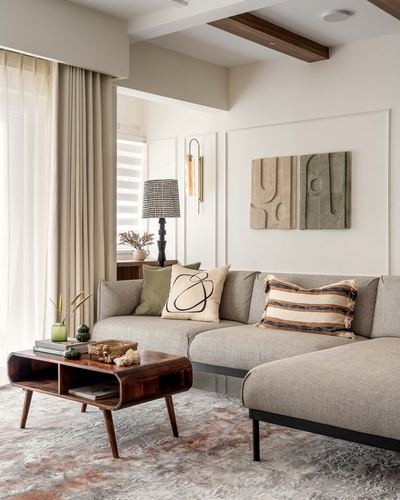 Beige sectional sofa with textured cushions beneath carved stone wall art, wooden coffee table in foreground