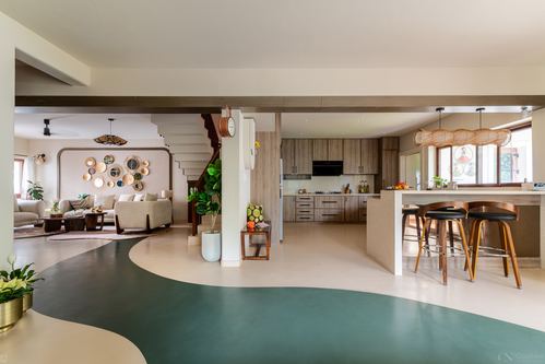 Open-plan home with curved green terrazzo floor connecting living room, staircase, and wood kitchen with island.