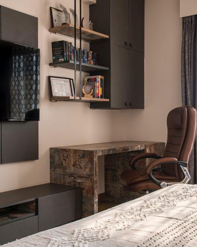 Study nook with stone waterfall desk, brown leather chair, floating shelves and wall-mounted tv