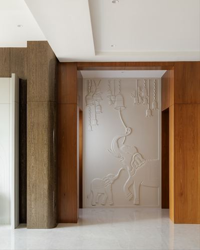 Foyer archway framed in wood panelling with a raised plaster relief of elephants and hanging bells on the far wall.