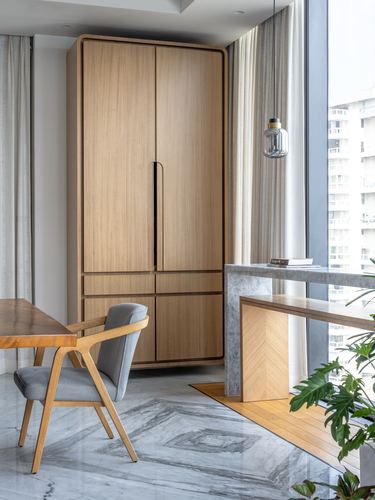 Curved wooden wardrobe beside marble console and desk with city view through glass wall