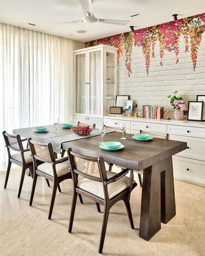 Dining room with dark wood table, cane chairs, white cabinetry and floral mural wall