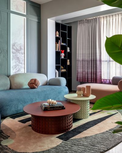 Living room with blue velvet sofa, terracotta pedestal coffee table, and patterned rug