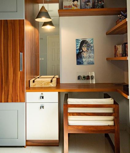 Wood-toned study nook with floating shelves, anime poster, pendant lights, and cushioned bench