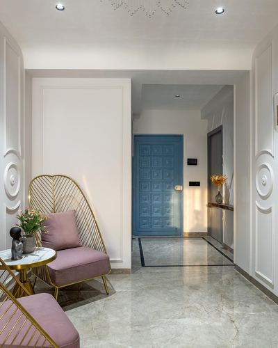 Foyer with pink velvet chairs, gold side table, and a paneled blue door beyond