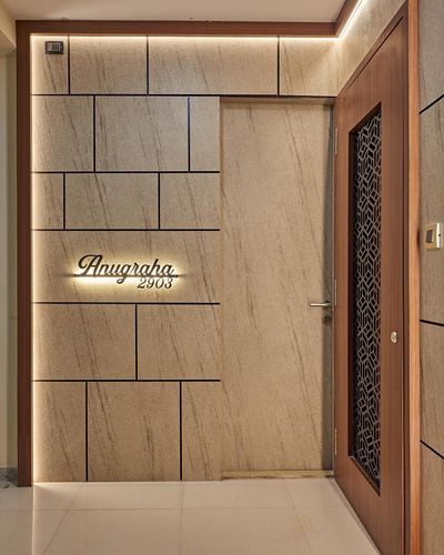 Entrance foyer with backlit stone wall panels, wooden door with jaali insert, and illuminated nameplate
