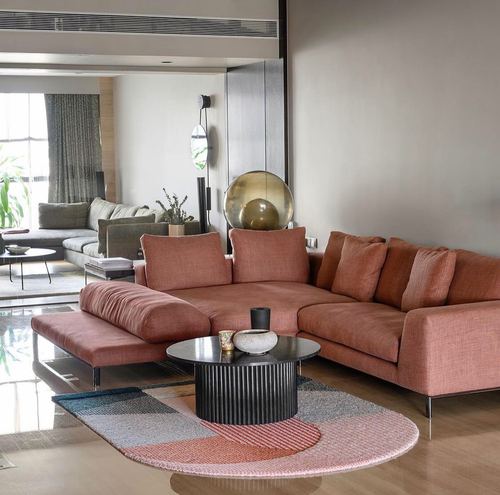 Terracotta sectional sofa with fluted black coffee table on a color-blocked rug in a modern living room