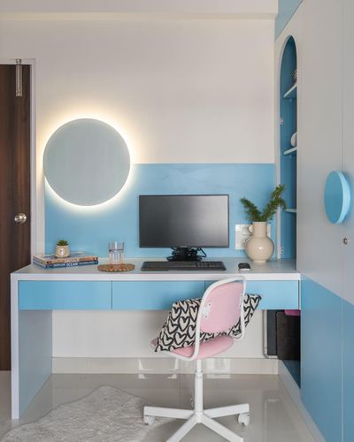 Blue and white study desk with backlit round mirror, monitor, and pink chair