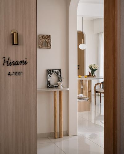 Foyer with wood door, brass sconce, console table, and arched opening to dining room