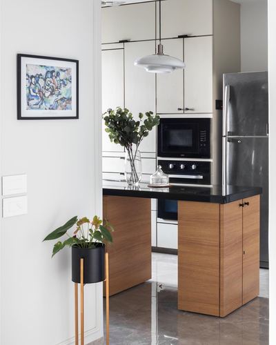 Kitchen with wood island, black stone counter, white cabinetry, steel fridge and framed art on wall