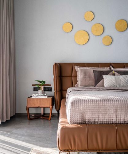 Bedroom with tan leather headboard, wooden nightstand, and gold circular wall discs