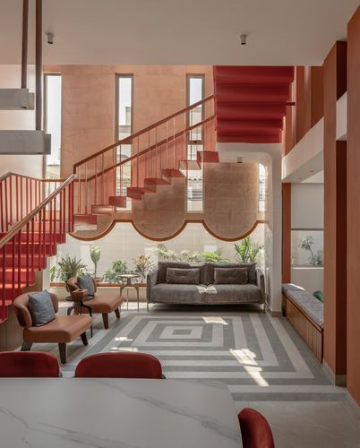 Living room with red cantilevered staircase, scalloped arch, grey sofa and geometric rug