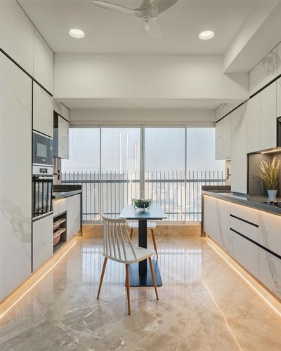 Galley kitchen with white marble-look cabinetry, small dining table, and floor-to-ceiling city view windows