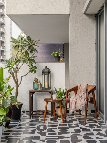 Balcony with patterned black-white tile, wooden chair, lanterns, and potted plants