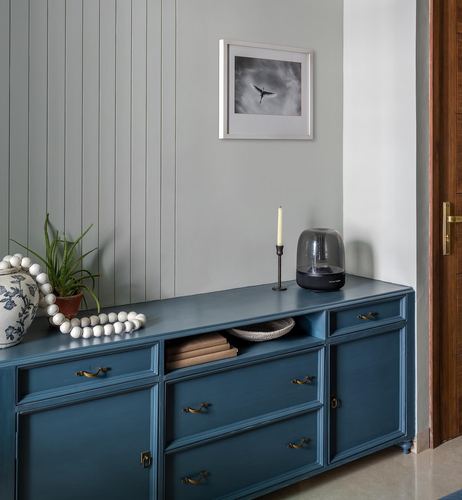 Teal painted sideboard against fluted sage green paneling with framed bird photograph above