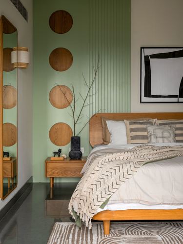Bedroom with sage green fluted wall, circular wood discs, wooden bed and mirror